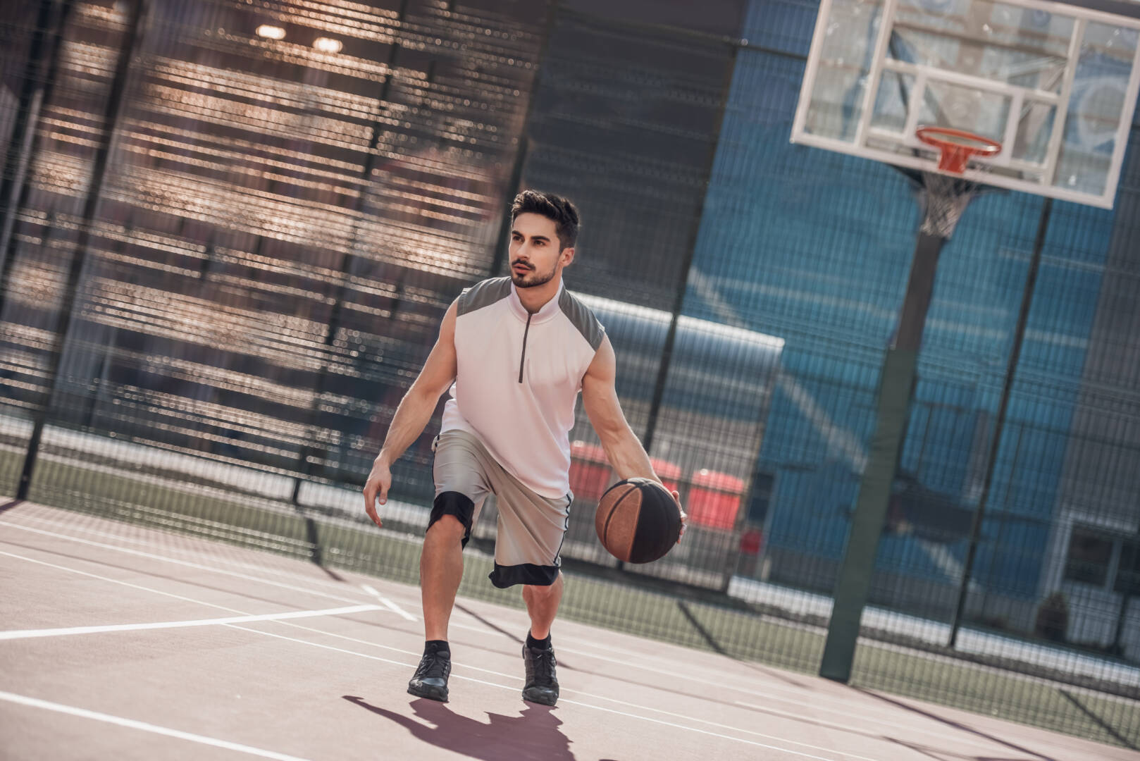 Handsome basketball player is playing on basketball court outdoors